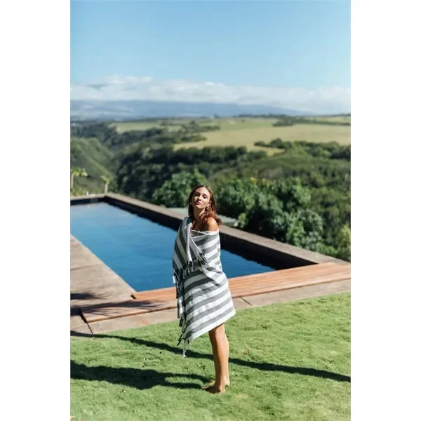 girl standing next to pool with branded sustainable merch slowtide beach towel