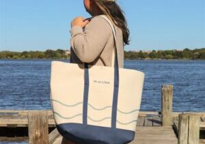 woman holding a tote bag made of heavy weight natural canvas with blue colored canvas trim with a snap closure